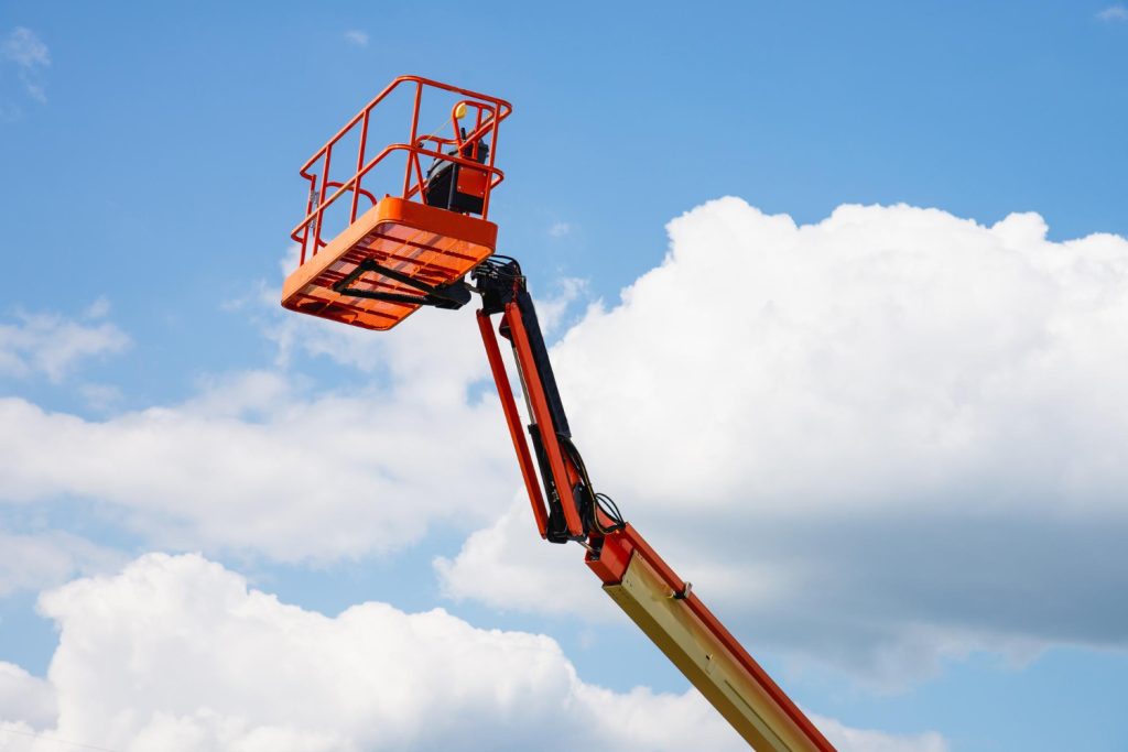 Hoogwerker categorieën: giekhoogwerker met oranje werkbak tegen een blauwe lucht